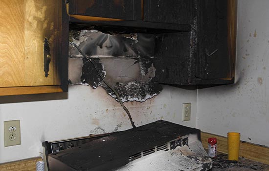 Fire damaged cabinets and stove in a kitchen